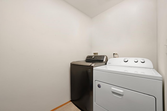 laundry area with independent washer and dryer, light tile patterned floors, laundry area, and baseboards
