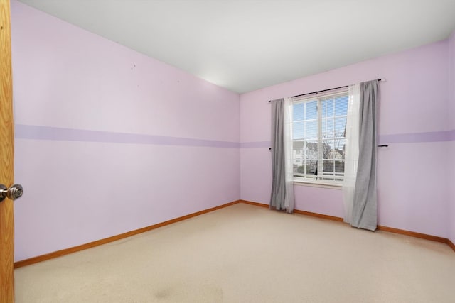 carpeted empty room featuring baseboards