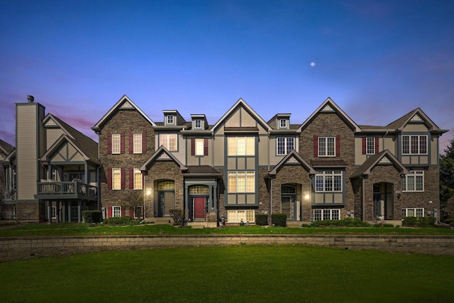 view of front of home with stucco siding, a yard, and stone siding