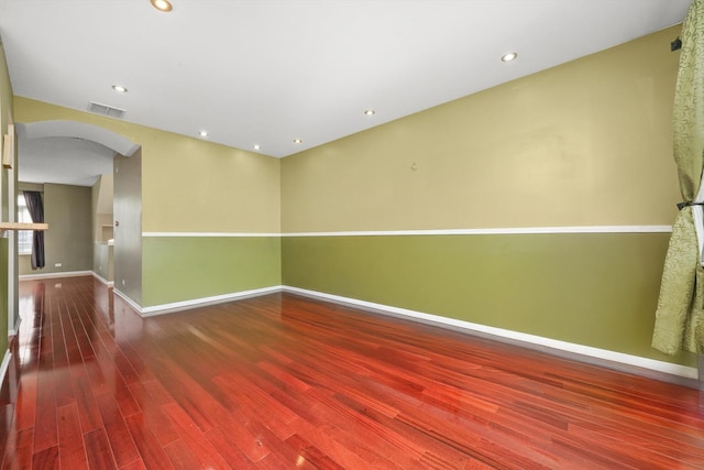 spare room with visible vents, wood finished floors, baseboards, recessed lighting, and arched walkways