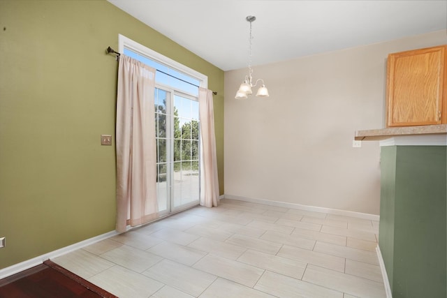 unfurnished dining area with an inviting chandelier and baseboards
