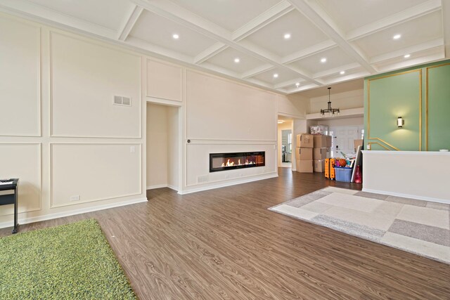 living area with visible vents, coffered ceiling, a decorative wall, and wood finished floors