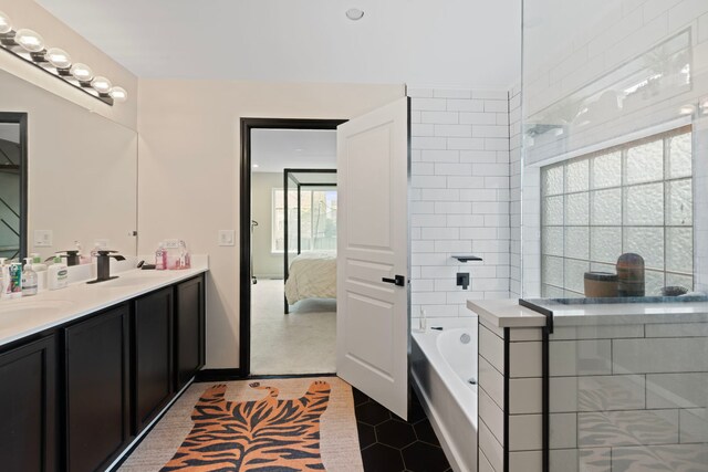 ensuite bathroom with double vanity, a tile shower, a sink, ensuite bathroom, and a tub to relax in
