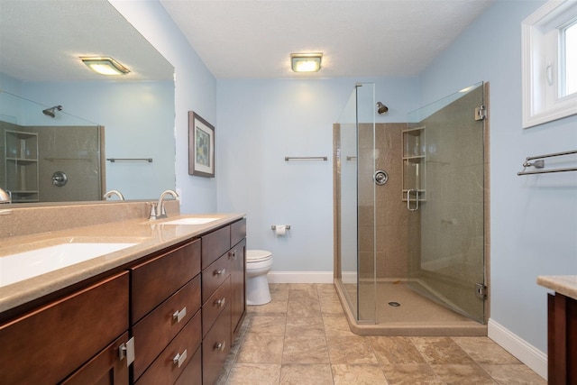 full bath featuring double vanity, baseboards, a shower stall, and a sink