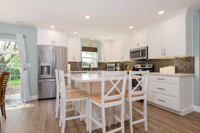 kitchen featuring decorative backsplash, light wood finished floors, white cabinets, and stainless steel appliances