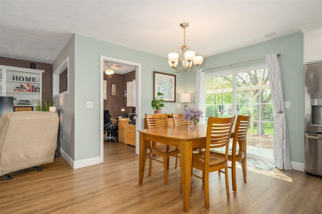 dining area with baseboards, light wood-style flooring, and ceiling fan with notable chandelier