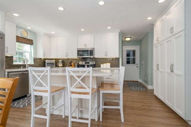 kitchen featuring white cabinets, tasteful backsplash, and stainless steel appliances