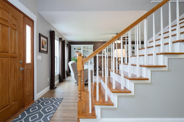 foyer featuring stairs, baseboards, and wood finished floors