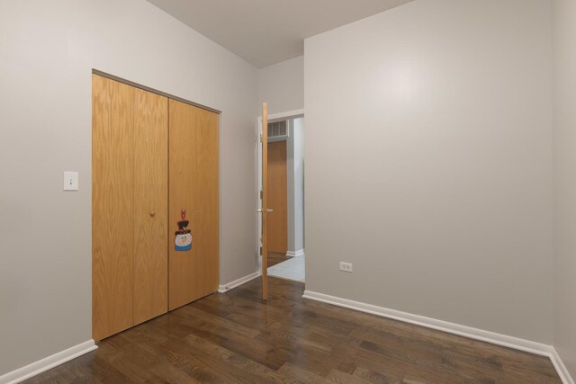 empty room with visible vents, baseboards, and dark wood-type flooring