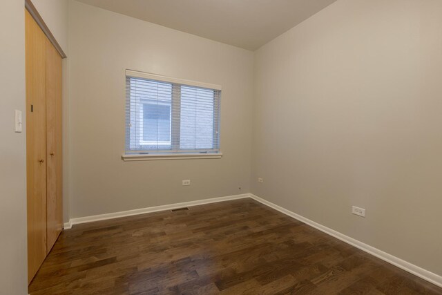 unfurnished bedroom featuring baseboards, dark wood-style floors, and a closet