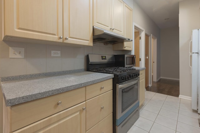 kitchen featuring tasteful backsplash, light brown cabinets, stainless steel appliances, under cabinet range hood, and light tile patterned flooring