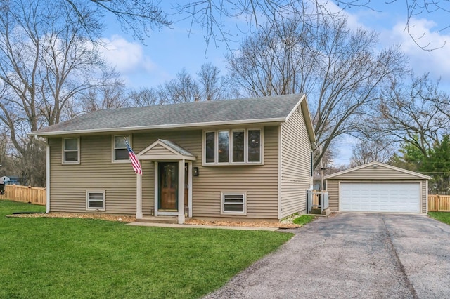 bi-level home with a detached garage, an outbuilding, a front yard, and fence