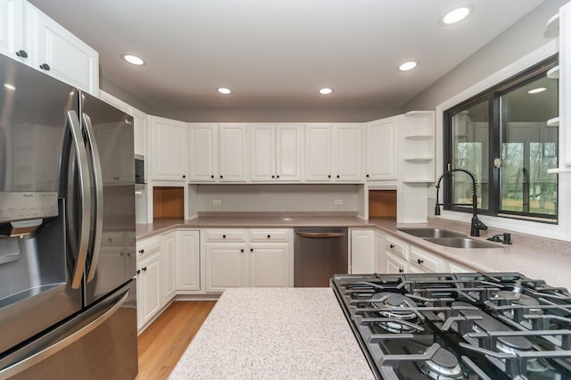 kitchen featuring stainless steel appliances, light countertops, a sink, and white cabinetry