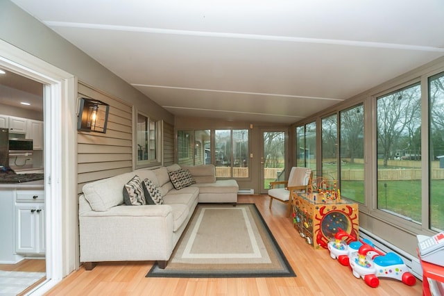 sunroom / solarium featuring a baseboard heating unit, vaulted ceiling, an outdoor hangout area, and wood finished floors