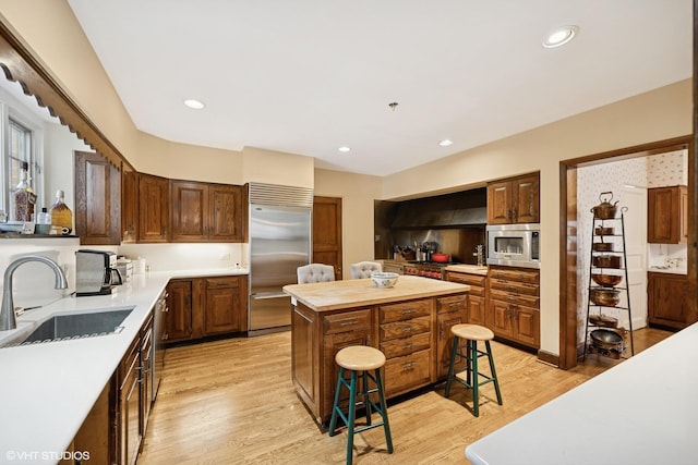 1250 Westmoor Rd, Winnetka, IL 60093 - kitchen with built in appliances, a sink, a kitchen breakfast bar, light wood-type flooring, and a center island