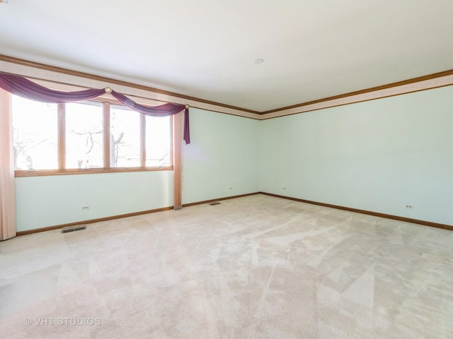 carpeted empty room featuring visible vents, baseboards, and ornamental molding