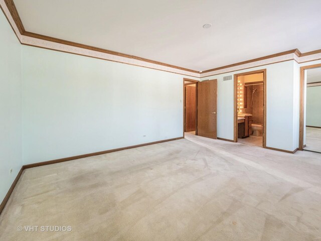 unfurnished bedroom featuring light carpet, visible vents, baseboards, crown molding, and connected bathroom