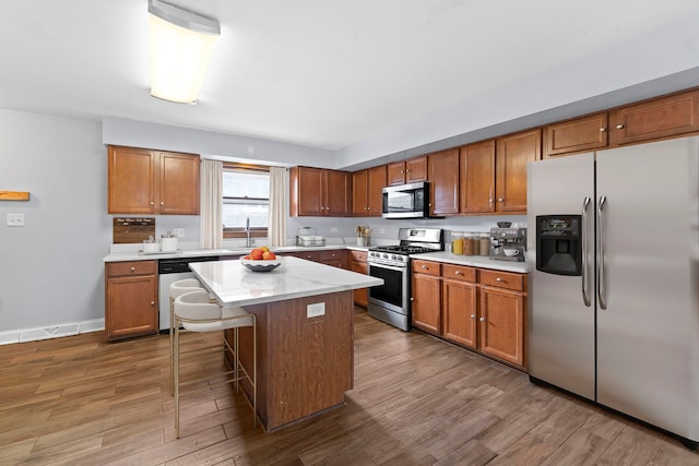 17148 William St, Lansing, IL 60438 - kitchen featuring brown cabinetry, stainless steel appliances, a kitchen island, light countertops, and dark wood-style floors