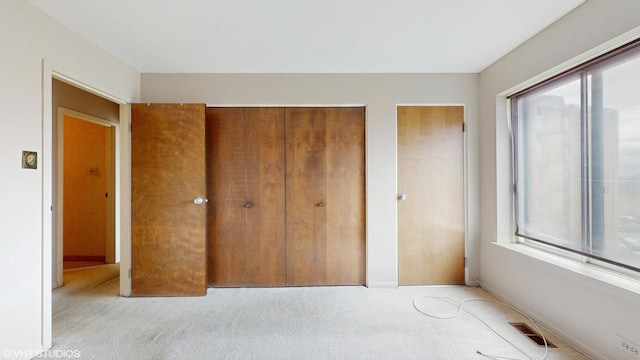 unfurnished bedroom featuring two closets, visible vents, and carpet flooring