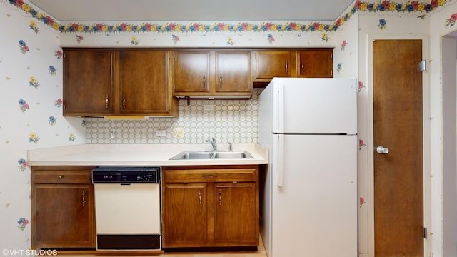 kitchen with a sink, decorative backsplash, wallpapered walls, white appliances, and light countertops