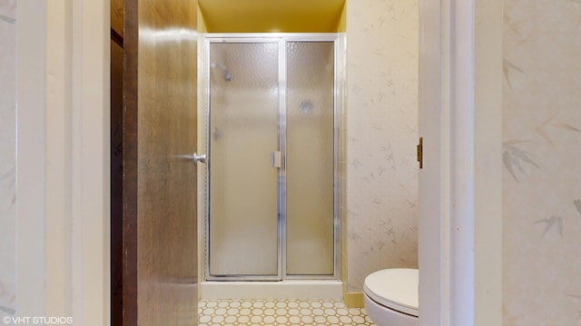 full bathroom featuring toilet, a shower stall, and wallpapered walls
