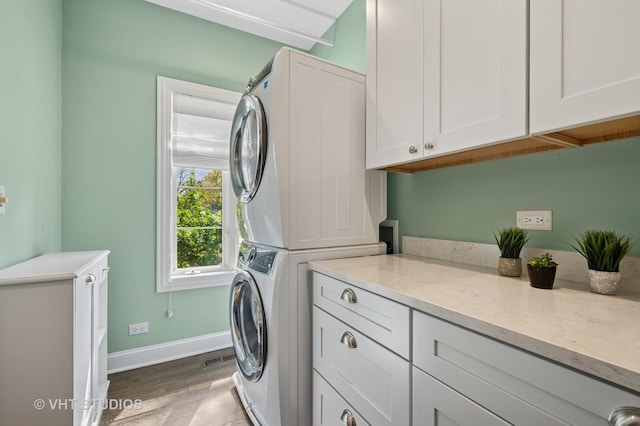 3118 Oliver Ln, Northbrook, IL 60062 - clothes washing area with cabinet space, stacked washing machine and dryer, wood finished floors, and baseboards