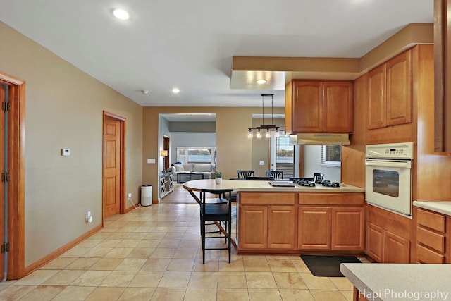 kitchen featuring recessed lighting, under cabinet range hood, white appliances, a peninsula, and light countertops