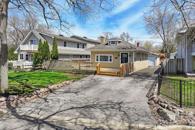 view of front facade featuring a chimney, a detached garage, an outbuilding, fence, and a front lawn