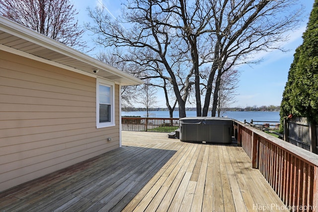 deck with a water view and a hot tub
