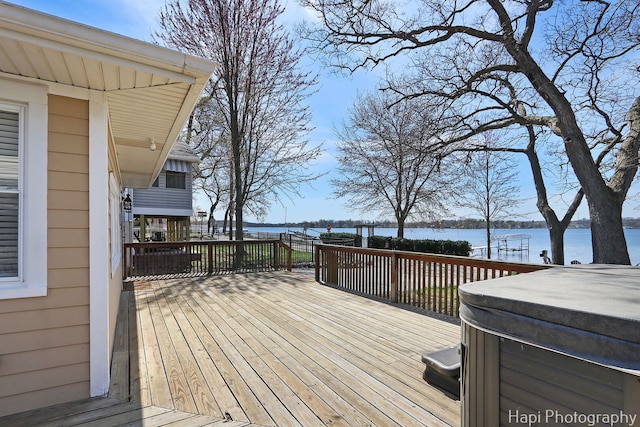 deck with a water view and a hot tub