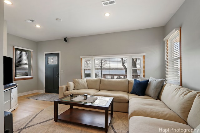 living area featuring baseboards, visible vents, light wood-type flooring, and plenty of natural light