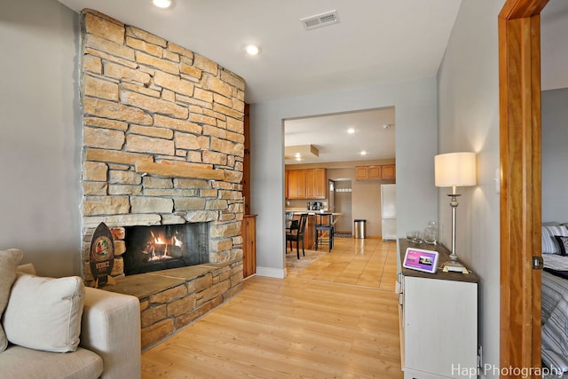 living area with a fireplace, visible vents, recessed lighting, and light wood finished floors