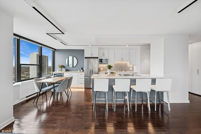 1560 N Sandburg Ter Unit 2301J, Chicago, IL 60610 - kitchen featuring dark wood finished floors, stainless steel appliances, light countertops, a kitchen bar, and white cabinetry