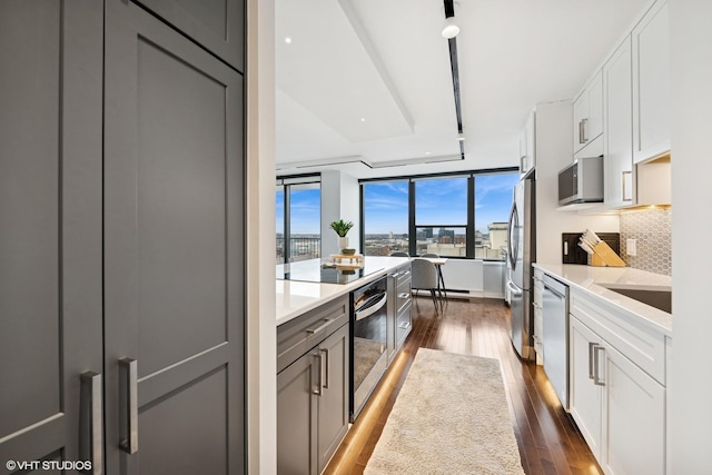 1560 N Sandburg Ter Unit 2301J, Chicago, IL 60610 - kitchen with decorative backsplash, stainless steel appliances, light countertops, white cabinets, and dark wood-style flooring