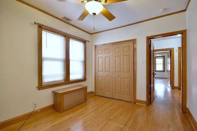 unfurnished bedroom featuring light wood-type flooring, baseboards, visible vents, a closet, and ornamental molding