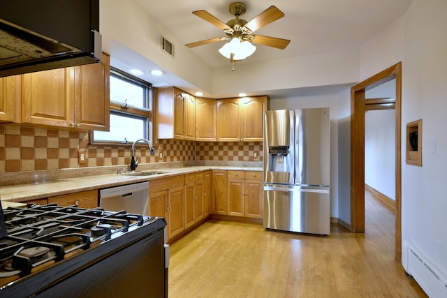kitchen with stainless steel appliances, a sink, visible vents, baseboard heating, and light countertops