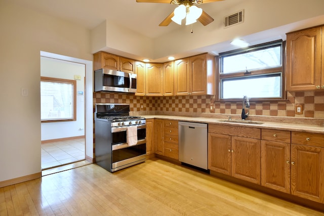 kitchen featuring light wood finished floors, stainless steel appliances, a sink, visible vents, and a ceiling fan