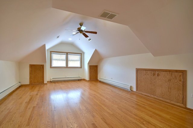 additional living space with a baseboard heating unit, lofted ceiling, visible vents, and a baseboard radiator