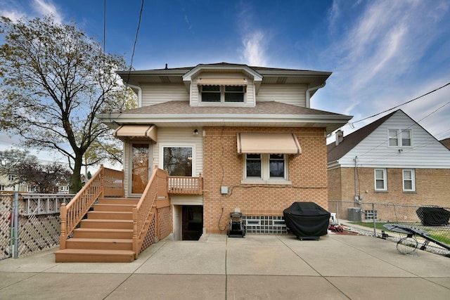back of house featuring brick siding, a patio area, a shingled roof, and fence