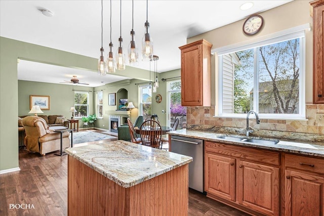 kitchen featuring dark wood-style flooring, a center island, light stone counters, a sink, and dishwasher
