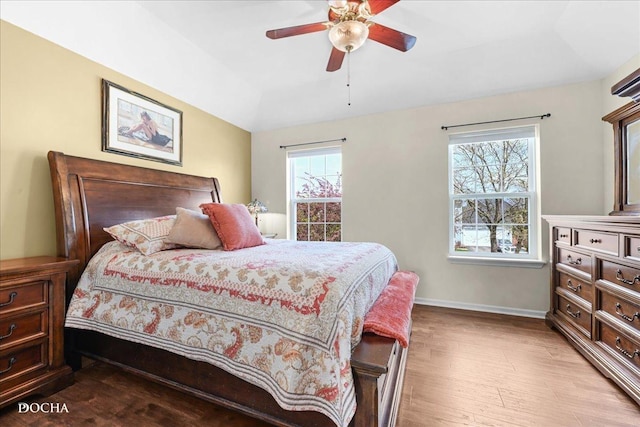 bedroom with a ceiling fan, baseboards, vaulted ceiling, and light wood-style floors