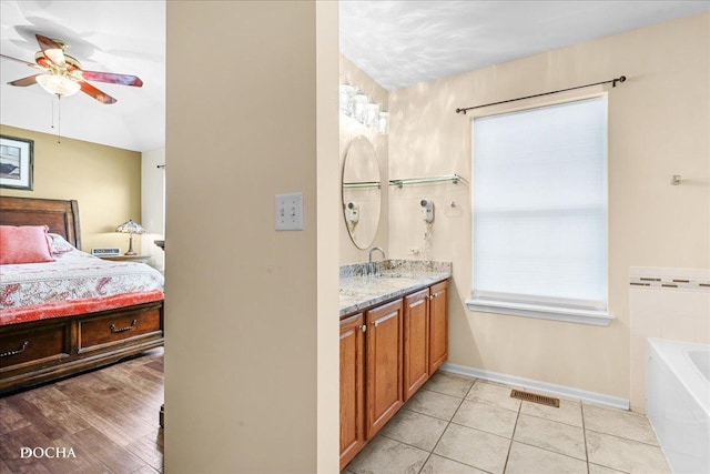 ensuite bathroom with a ceiling fan, visible vents, vanity, a bathing tub, and connected bathroom