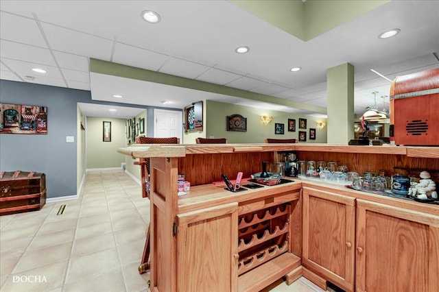 bar featuring indoor wet bar, baseboards, and a paneled ceiling