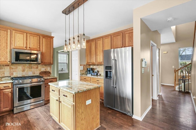 kitchen with a kitchen island, dark wood-style flooring, tasteful backsplash, light stone countertops, and stainless steel appliances