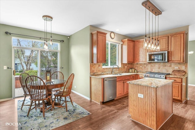 kitchen with baseboards, appliances with stainless steel finishes, wood finished floors, and tasteful backsplash