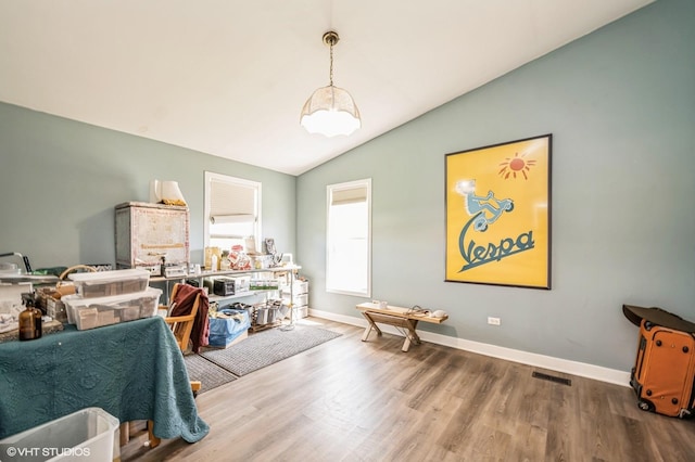 interior space featuring visible vents, vaulted ceiling, wood finished floors, and baseboards