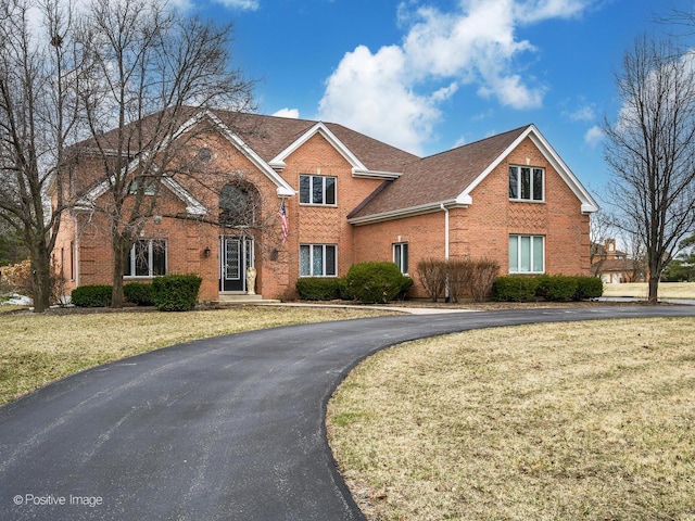view of front of home featuring a front lawn, brick siding, and aphalt driveway