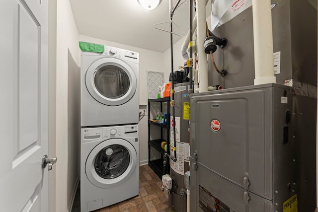laundry area with laundry area, stone finish flooring, stacked washing maching and dryer, water heater, and heating unit
