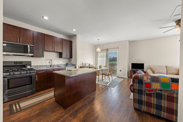 kitchen featuring dark wood finished floors, a center island, stainless steel appliances, open floor plan, and recessed lighting