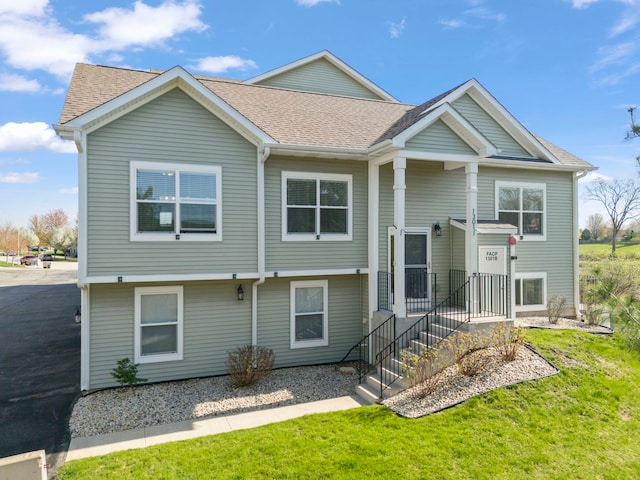 raised ranch with a shingled roof and a front lawn